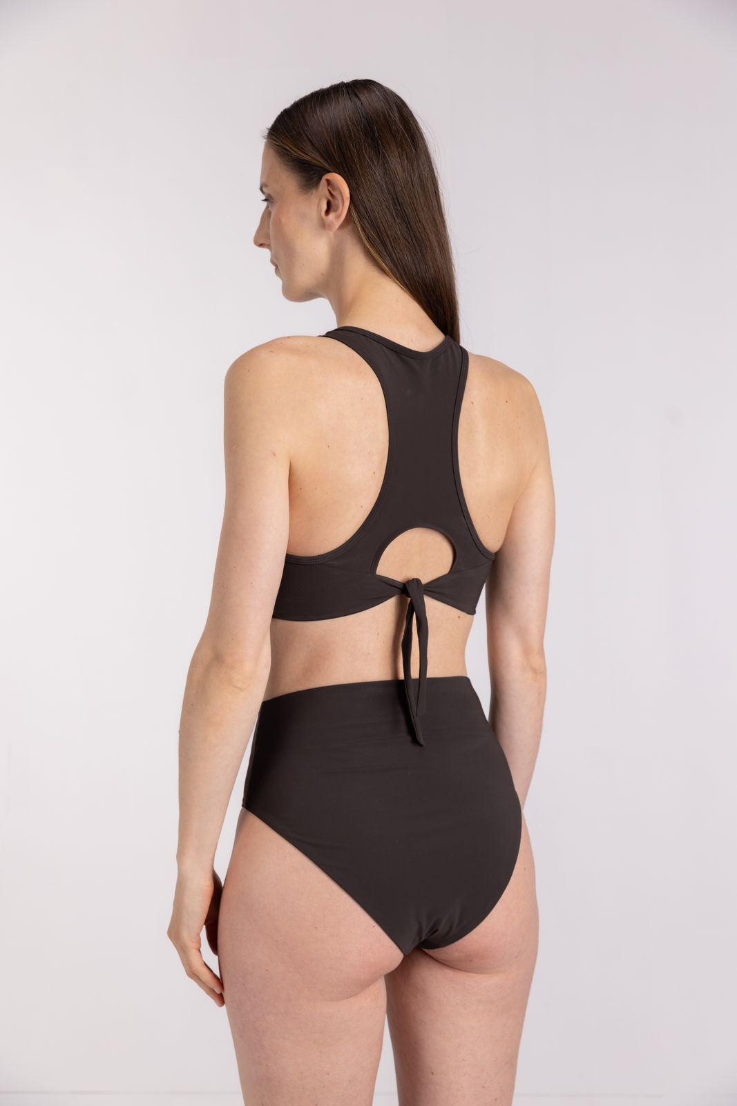 Back view of model wearing coffee high waist bikini bottom and racer top, ideal for water sports, on light studio background
