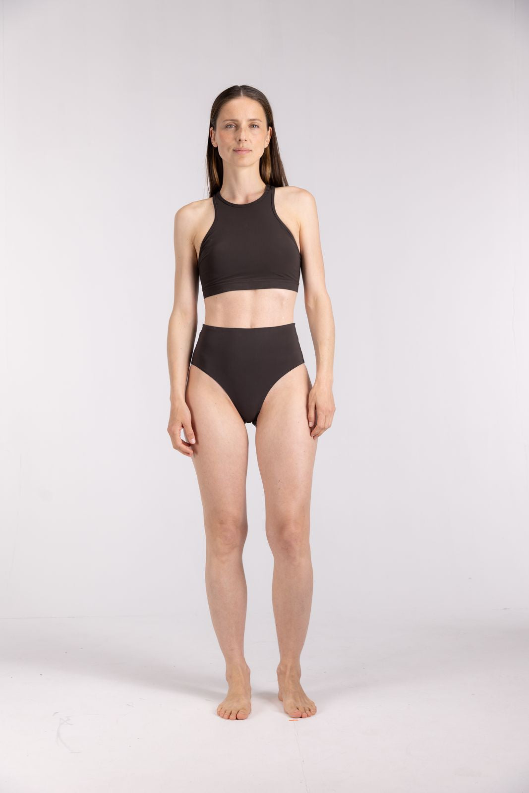 Full body view of woman wearing WALLIEN coffee high waist bikini bottom made for surfing and water sports, on white backdrop