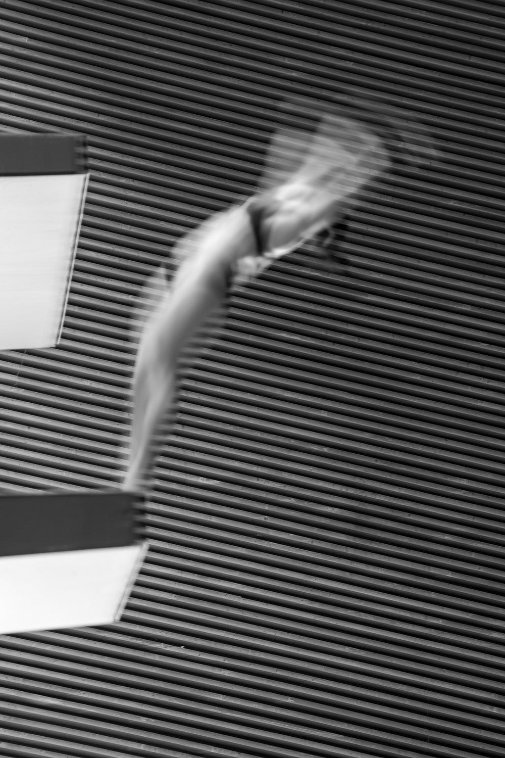 Woman mid-dive in black bikini top with cross-back straps, motion-blurred to show speed and flow in high-performance swimwear