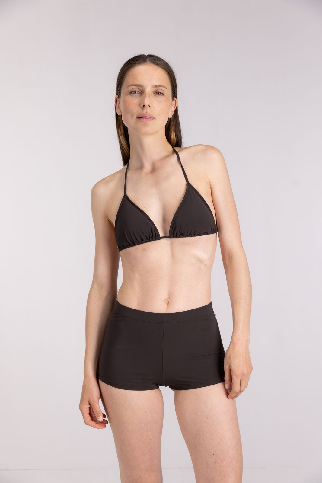 Woman in coffee triangle bikini top and hot pants posing for summer beachwear, activewear shoot, on white studio background