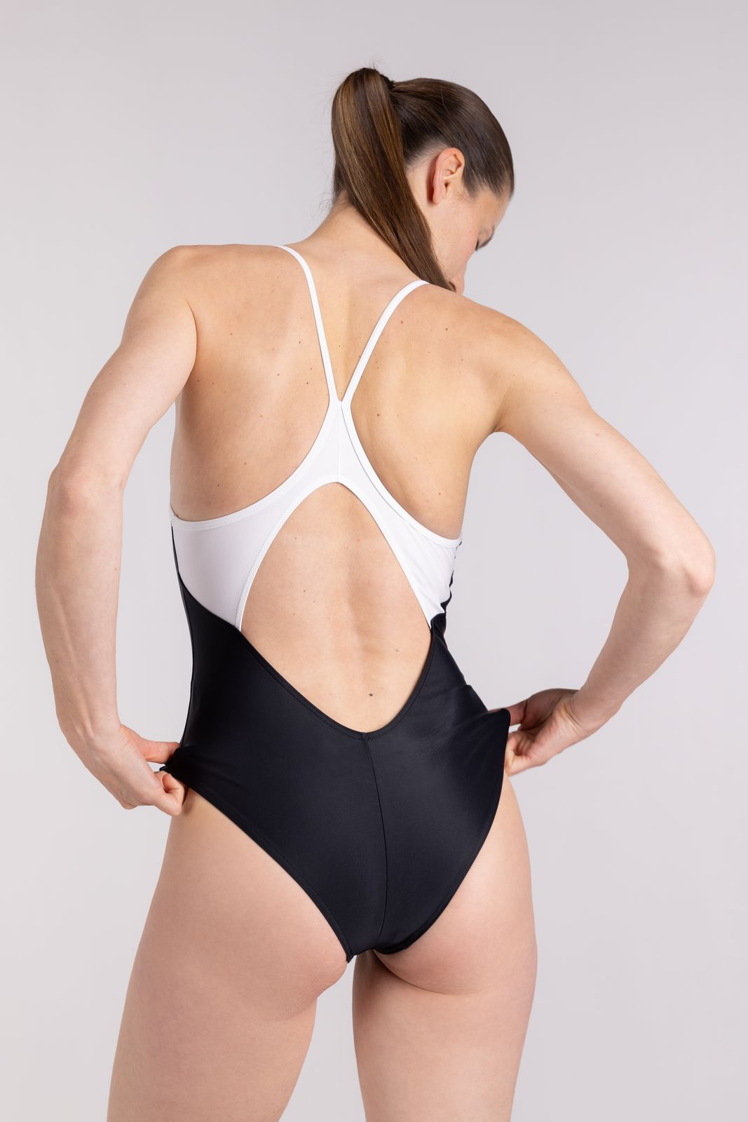 Rear view of racerback WALLIEN swimsuit showing cut-out back and white shoulder straps, for swim sessions, studio background