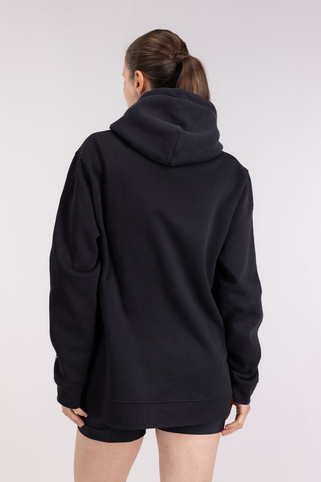 Rear view of cozy Black Ocean Hoodie with spacious hood and drop-shoulder cut, for after-swim session on studio background