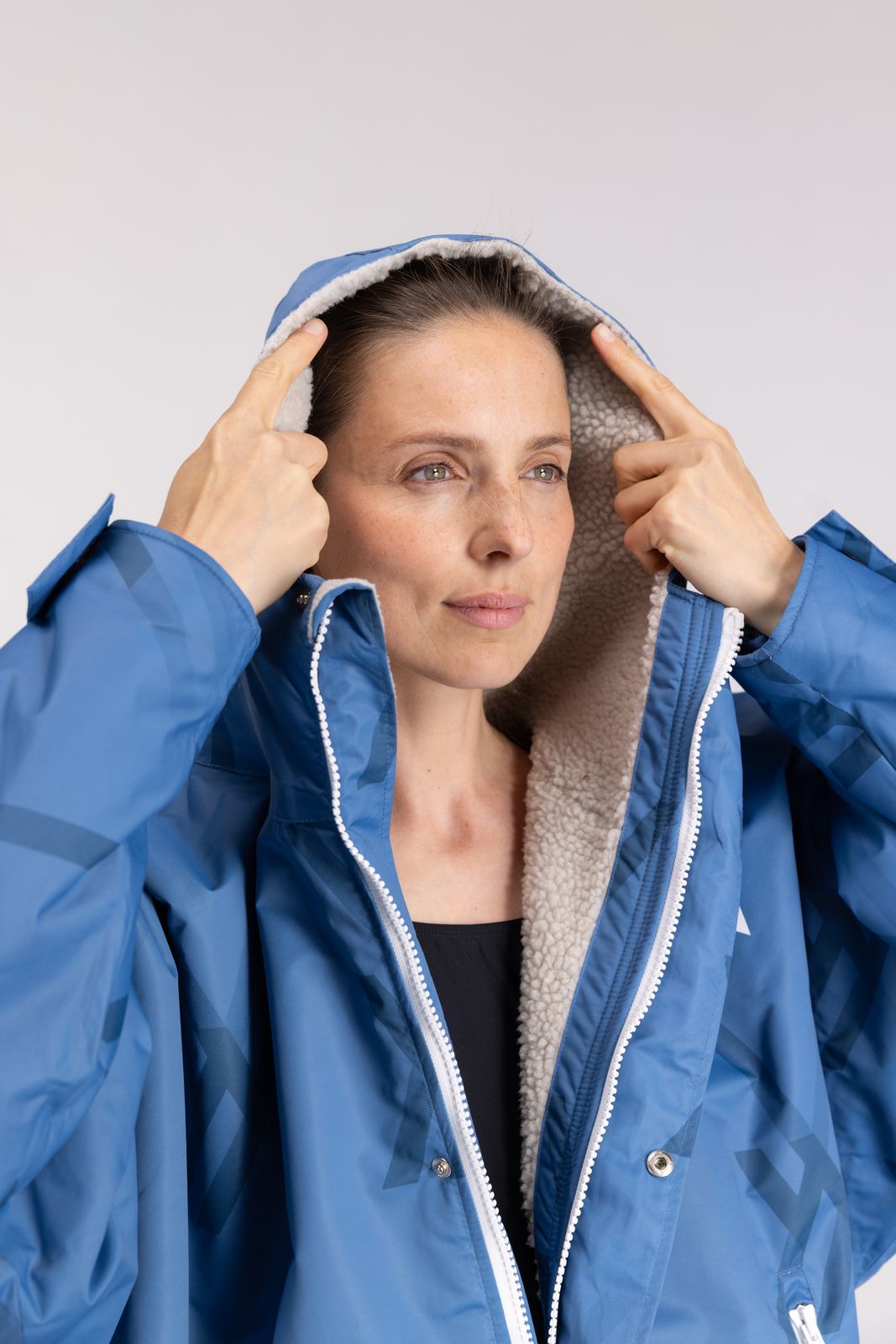 Close-up of model wearing WALLIEN changing robe in blue, hood up with sherpa lining, swim-ready look on studio background