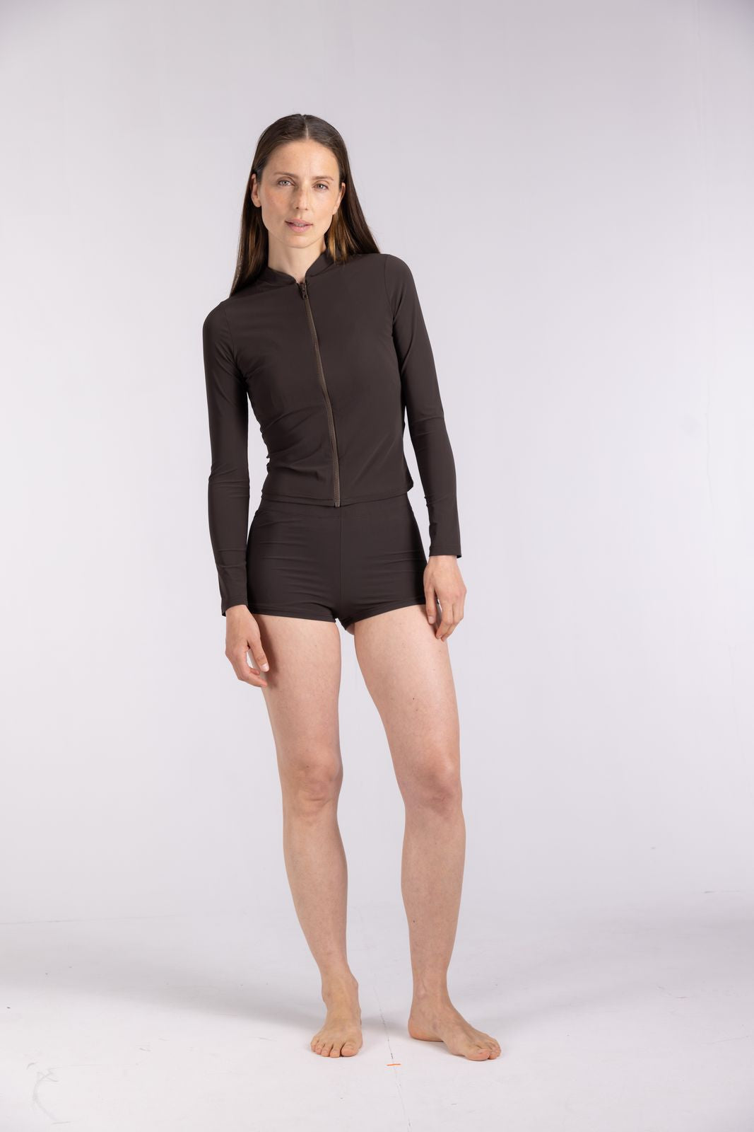 Full-body shot of woman in WALLIEN Rash Guard With Zip in Coffee, designed for surf layering, white studio background