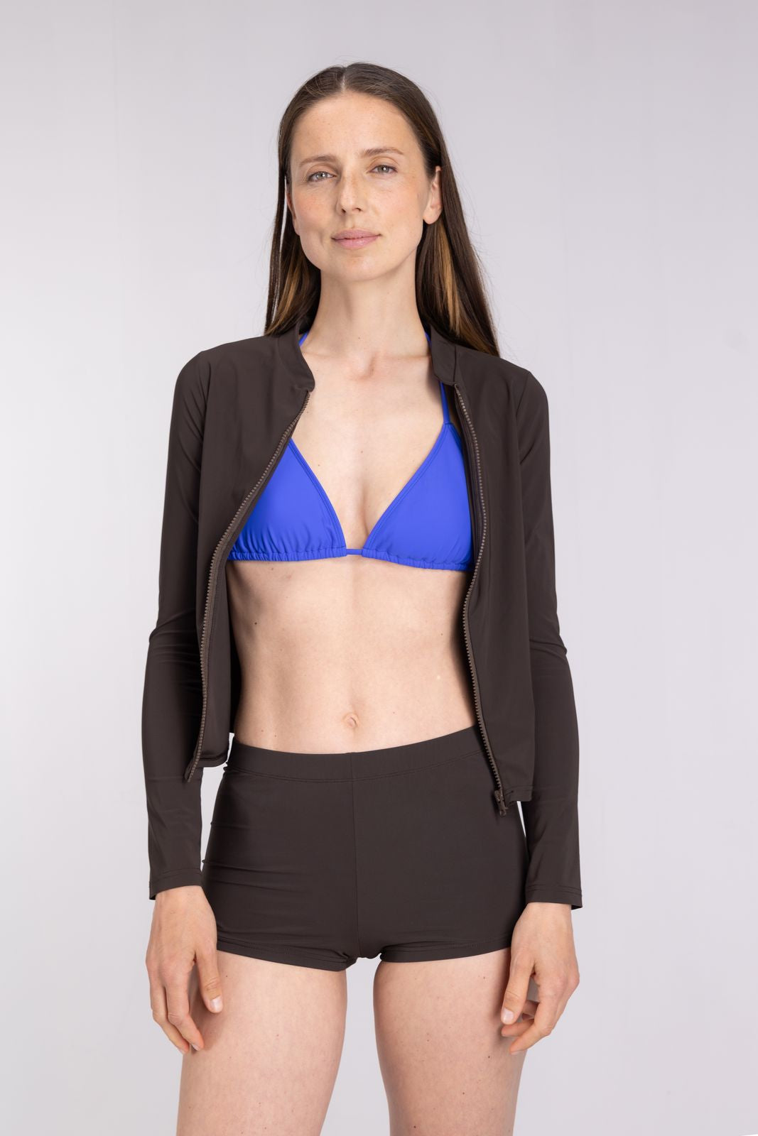Rash Guard With Zip in Coffee layered over blue bikini top, styled for warm-up or sun protection, plain studio background