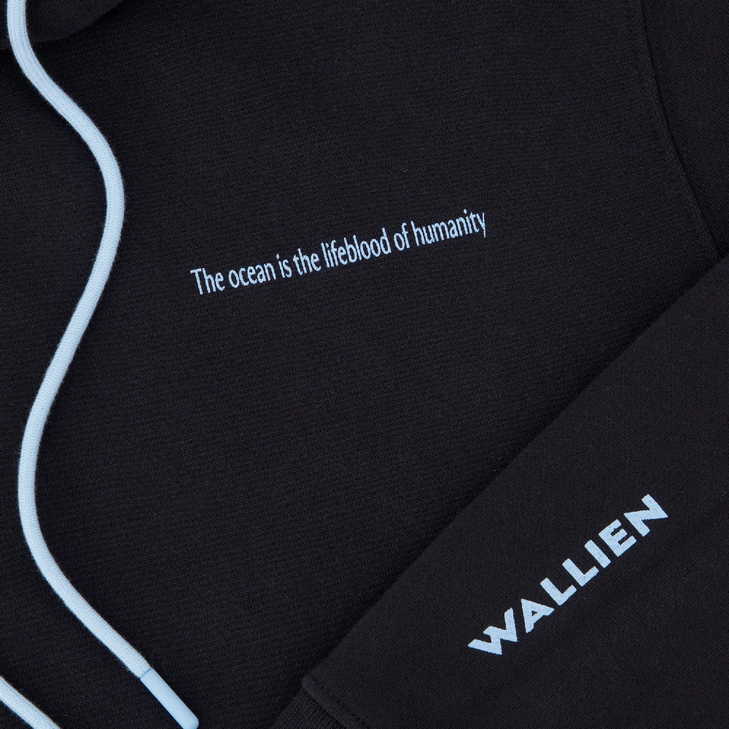 Close-up of black Ocean Hoodie fabric with clean seams, WALLIEN branding and quote ‘The ocean is the lifeblood of humanity’